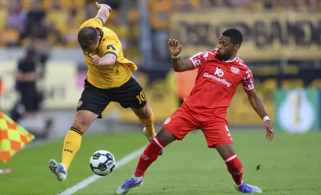 Dresden's Jakob Lemmer, left, and Mainz' Arnaud Nordin, right, challenge for the ball during the German soccer cup first round match between Dynamo Dresden and FSV Mainz 05 in Dresden, Germany, Monday, Aug. 18, 2025. (Robert Michael/dpa via AP)