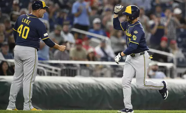 Milwaukee Brewers' Blake Perkins, right, celebrates his two-run home run with third base coach Jason Lane (40) during the fifth inning of a baseball game against the Washington Nationals, Friday, Aug. 1, 2025, in Washington. (AP Photo/Nick Wass)