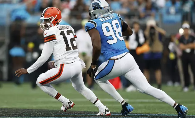Cleveland Browns quarterback Shedeur Sanders is pursued by Carolina Panthers linebacker D.J. Wonnum during the first half of a preseason NFL football game on Friday, Aug. 8, 2025, in Charlotte, N.C. (AP Photo/Rusty Jones)