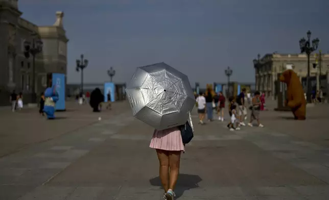A woman protects herself with an umbrella during a heat wave in Madrid, Spain, Tuesday, Aug. 12, 2025. (AP Photo/Manu Fernandez)