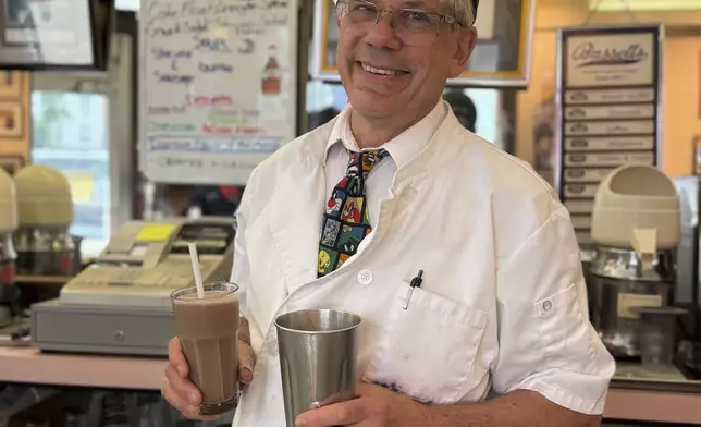 John Philis poses with a chocolate milkshake at the Lexington Avenue Candy Shop Luncheonette in New York on Aug. 7, 2025. (Katie Workman via AP)
