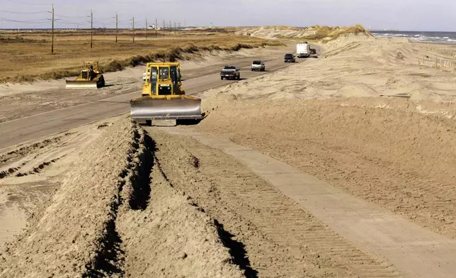 FILE - A bulldozer pushes sand along NC highway 12 in the Pea island National Wildlife Refuge, on North Carolina's Outer Banks, near Nags Head, N.C., Dec. 18, 2003, as workers rebuild dunes that were destroyed by Hurricane Isabel. (AP Photo/Bob Jordan, File)
