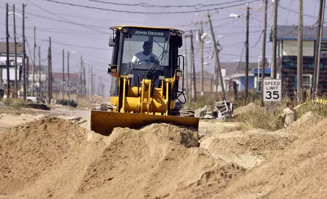 FILE - A bulldozer clears sand from N.C. highway 12, Sunday, Sept. 21, 2003, in Kill Devil Hills, N.C., after Hurricane Isabel hit North Carolina's Outer Banks. (AP Photo/Bob Jordan)