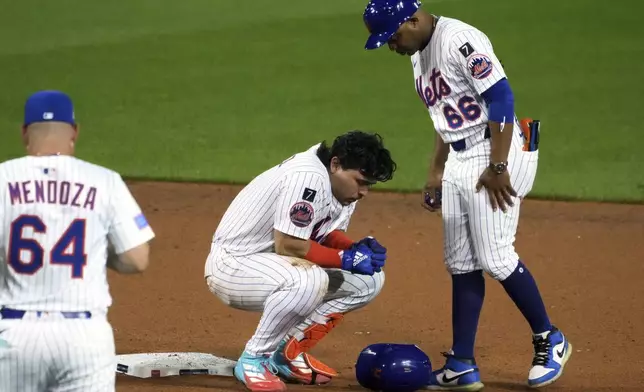 New York Mets' Francisco Alvarez, center, is tend to by first base coach Antoan Richardson (66) and manager Carlos Mendoza after being injured sliding into second during the seventh inning of the Little League Classic baseball game against the Seattle Mariners at Bowman Field in Williamsport, Pa., Sunday, Aug. 17, 2025. (AP Photo/Gene J. Puskar)