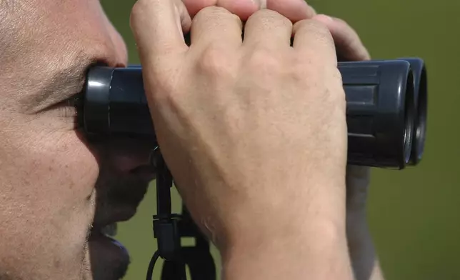 FILE - Jim Rapp, director of Delmarva Low-Impact Tourism Experiences, looks for birds through binoculars, Aug. 15, 2007 in Girdletree, Md. (AP Photo/Matthew S. Gunby, file)