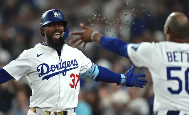 Los Angeles Dodgers' Teoscar Hernández, left, is hit with seeds thrown by Mookie Betts after hitting a solo home run during the seventh inning of a baseball game against the San Diego Padres, Friday, Aug. 15, 2025, in Los Angeles. (AP Photo/Mark J. Terrill)