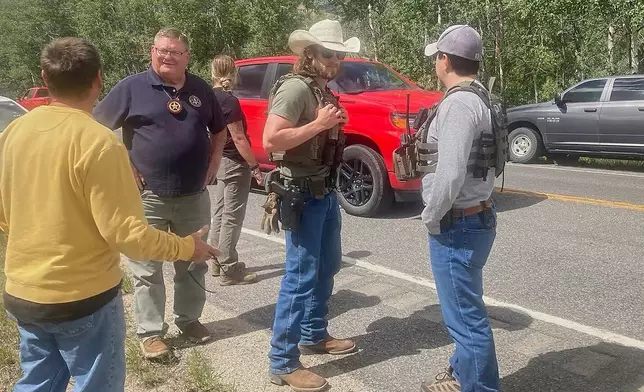 Law enforcement officers stand at the scene where Michael Brown, a suspect in a shooting at a Montana bar that left four people dead, was apprehended on Friday, Aug. 8, 2025, outside of Anaconda, Mont. (Duncan Adams/The Montana Standard via AP)