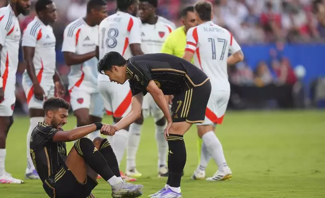 Los Angeles FC forward Heung Min Son (7) offers a hand to teammate forward Denis Bouanga, front left, after Bouanga was fouled by FC Dallas during the first half of an MLS soccer match in Frisco, Texas, Saturday, Aug. 23, 2025. (AP Photo/LM Otero)