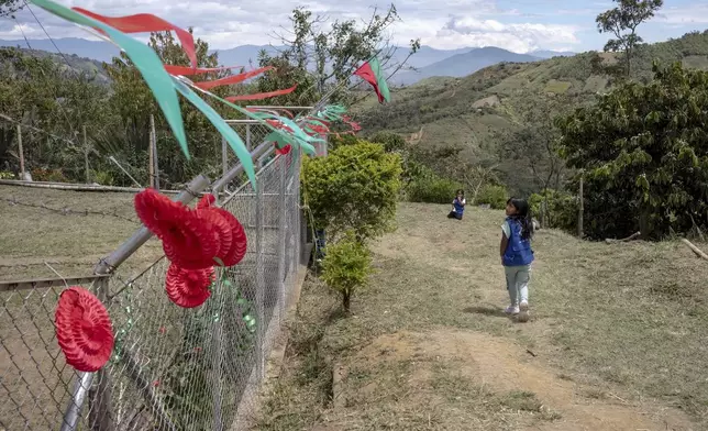 Children walk by decorations in the colors of red and green — which represent blood and earth, July 18, 2025, in Manuelico village, Caldono, Colombia. (AP Photo/Nadège Mazars)