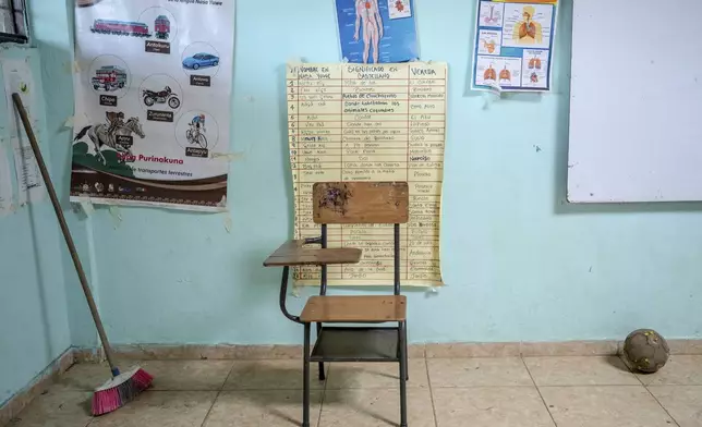 In a classroom at a school, a desk sits near posters displaying educational information, some in the Nasa Yuwe language, on July 18, 2025, in Manuelico village, Caldono, Colombia. (AP Photo/Nadège Mazars)