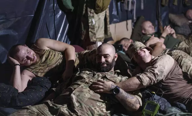 Ukrainian servicemen of the 148th artillery brigade rest in a dugout at the frontline in Zaporizhzhia region, Ukraine, on Thursday, Aug. 7, 2025. (AP Photo/Evgeniy Maloletka)