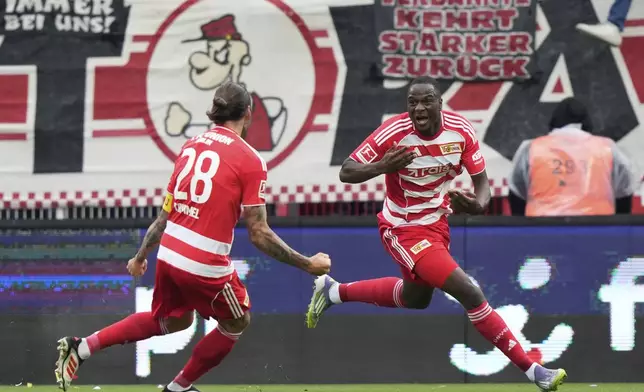 Union's Ilyas Ansah, right, celebrates with Union's Christopher Trimmel after scoring the opening goal during the German Bundesliga soccer match between FC Union Berlin and VfB Stuttgart, at the An der Alten Forsterei stadium in Berlin, Germany, Saturday, Aug. 23, 2025. (AP Photo/Ebrahim Noroozi)