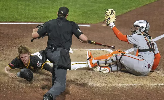 As umpire Ryan Addison, center, makes the call, Pittsburgh Pirates' Jack Suwinski, left, scores a walkoff winning run ahead of a tag by San Francisco Giants catcher Patrick Bailey, right, on a fielder's choice hit into by Isiah Kiner-Falefa off pitcher Randy Rodríguez during the ninth inning of a baseball game in Pittsburgh, Monday, Aug. 4, 2025. (AP Photo/Gene J. Puskar)