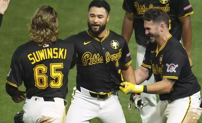 Pittsburgh Pirates' Isiah Kiner-Falefa, center, celebrates with Jack Suwinski (65) and Spencer Horwitz, right, after driving in a walkoff winning run with a fielder's choice off San Francisco Giants pitcher Randy Rodríguez during the ninth inning of a baseball game in Pittsburgh, Monday, Aug. 4, 2025. (AP Photo/Gene J. Puskar)