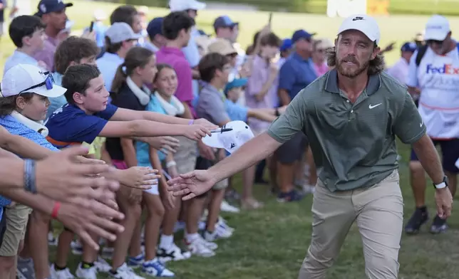 Tommy Fleetwood, of England, reaches to touch fans as he walks off the 18th green during the third round of the St. Jude Championship golf tournament Saturday, Aug. 9, 2025, in Memphis, Tenn. (AP Photo/George Walker IV)