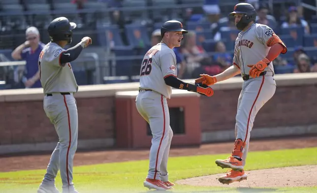 San Francisco Giants' Casey Schmitt, right, celebrates with Matt Chapman, center, and Dominic Smith after hitting a three-run homer during the ninth inning of a baseball game against the New York Mets, Sunday, Aug. 3, 2025, in New York. (AP Photo/Seth Wenig)
