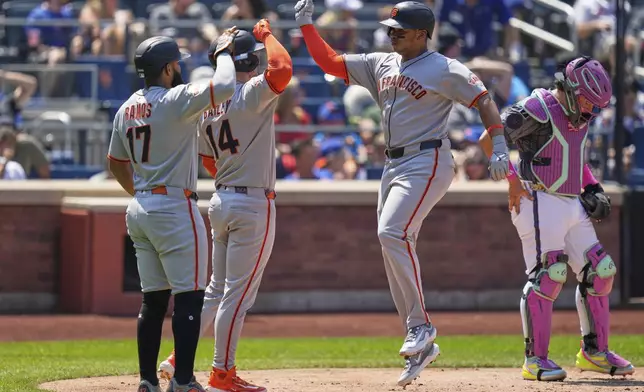 San Francisco Giants' Rafael Devers, second from right, celebrates with teammates Heliot Ramos, left, and Patrick Bailey, second from left, after hitting a three-run homer during the third inning of a baseball game against the New York Mets, Sunday, Aug. 3, 2025, in New York. (AP Photo/Seth Wenig)