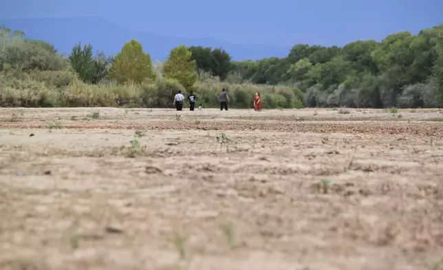 A family takes a walk in the Rio Grande's dry riverbed in Albuquerque, N.M., on Thursday, Aug. 21, 2025. (AP Photo/Susan Montoya Bryan)