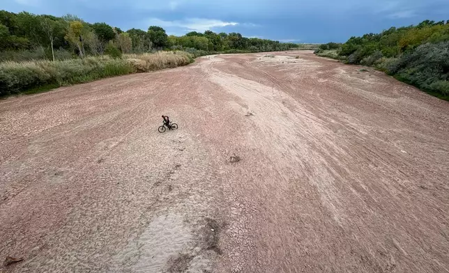 A bicyclist traverses the Rio Grande's dry riverbed in Albuquerque, N.M., on Thursday, Aug. 21, 2025. (AP Photo/Susan Montoya Bryan)