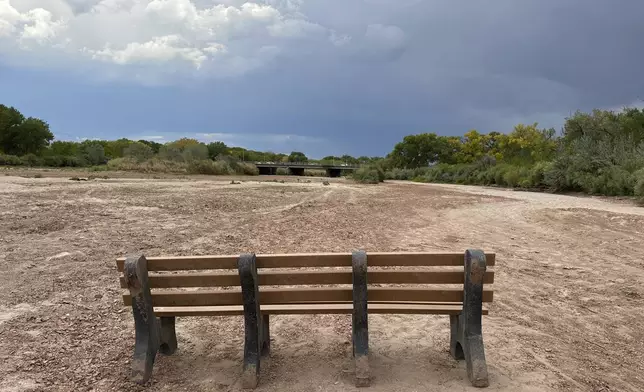 A park bench sits in the dry riverbed of the Rio Grande as traffic crosses a bridge along historic Route 66 in Albuquerque, N.M., on Thursday, Aug. 21, 2025. (AP Photo/Susan Montoya Bryan)
