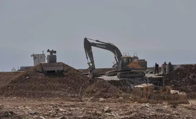 Workers stand beside a bulldozer at one of five new Israeli army positions built inside Lebanese territory along the road between Houla and Kfar Kila following airstrikes and a ground offensive that destroyed nearby villages, southern Lebanon, Wednesday, Aug. 20, 2025.(AP Photo/Hussein Malla)