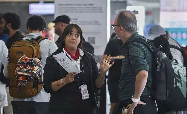An Air Canada agent, left, talks with a man as Air Canada flight attendants strike at Montreal-Pierre Elliott Trudeau International Airport in Montreal, Saturday, Aug. 16, 2025. (Graham Hughes/The Canadian Press via AP)