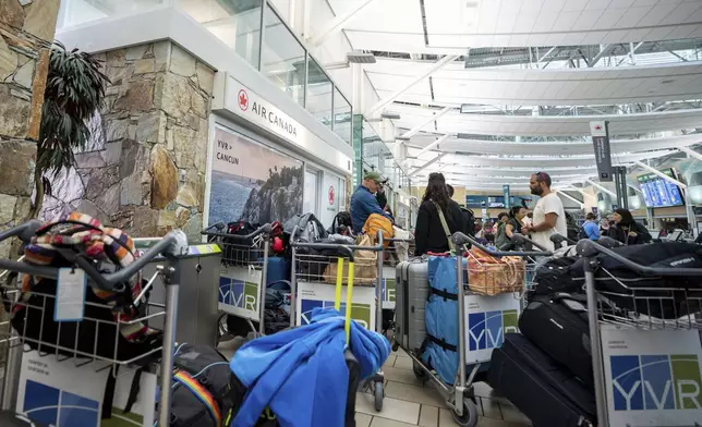 People wait outside of Air Canada check in at the Vancouver International Airport in Richmond, B.C., Canada, on Saturday, Aug. 16, 2025. (Ethan Cairns/The Canadian Press via AP)