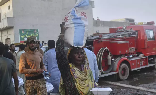A woman carries sack of food items as she walks back after getting it from a relief-camp set up by Pakistan army for flood victims on the outskirts of Sodhra town, in Wazirabad district, Pakistan, Aug. 28, 2025. (AP Photo/A. Rizvi)