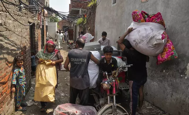 Residents retrieve belongings from their flooded home due to rising water level in Ravi River after torrential rains at a low-lying area on the outskirts of Lahore, Pakistan, Aug. 28, 2025. (AP Photo/K.M. Chaudary)
