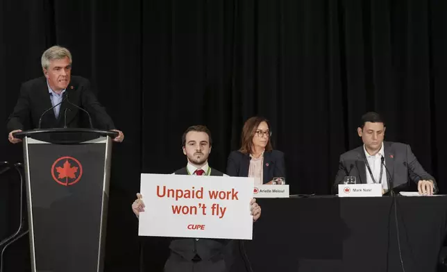 Air Canada executives are interrupted by Air Canada flight attendants during a press conference as a possible strike looms, in Toronto, on Thursday, Aug. 14, 2025. (Nathan Denette/The Canadian Press via AP)