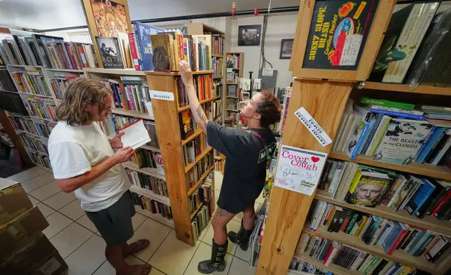 Andrew Higgins and Savannah Shealy peruse the biography section of the Green Hand Bookstore in Portland, Maine, on Thursday, Aug. 7, 2025. (AP Photo/Robert F. Bukaty)