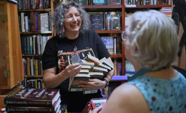 Owner Michelle Souliere, left, chats with a frequent customer at the Green Hand Bookstore in Portland, Maine, on Thursday, Aug. 7, 2025. (AP Photo/Robert F. Bukaty)