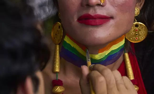 A participant paints her neck with rainbow colors during the Pride Parade in Kathmandu, Nepal, Sunday, Aug. 10, 2025. (AP Photo/Niranjan Shrestha)