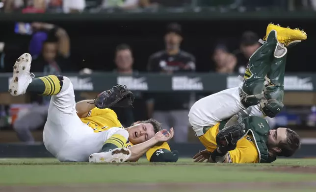 Athletics first baseman Nick Kurtz,left, and catcher Shea Langeliers, middle, react after colliding while attempting to catch a pop up during the seventh inning of a baseball game against the Arizona Diamondbacks, Saturday, Aug. 2, 2025, in West Sacramento, Calif. (AP Photo/Scott Marshall)