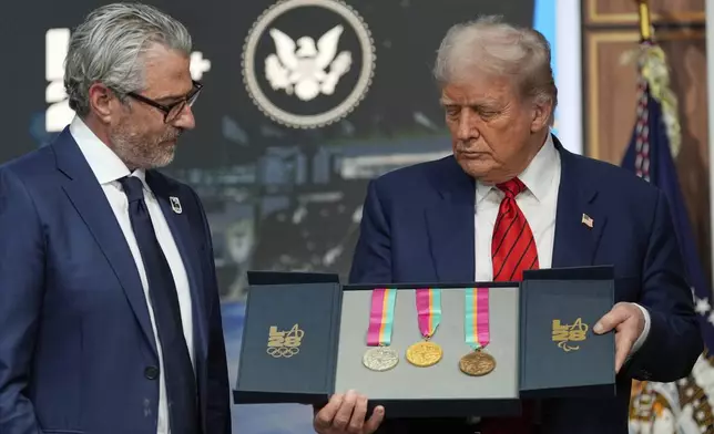 President Donald Trump listens as Casey Wasserman, chairman of LA28, presents him a full set of medals from the 1984 Olympics in Los Angeles, during an event regarding the 2028 Los Angeles Olympic Games, in the South Court Auditorium of the Eisenhower Executive Office Building on the White House campus, Tuesday, Aug. 5, 2025, in Washington. (AP Photo/Alex Brandon)