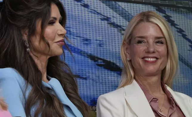 Attorney General Pam Bondi, right, and Homeland Security Secretary Kristi Noem listen as President Donald Trump speaks before signing an executive order about the 2028 Los Angeles Olympic Games, in the South Court Auditorium of the Eisenhower Executive Office Building on the White House campus, Tuesday, Aug. 5, 2025, in Washington. (AP Photo/Julia Demaree Nikhinson)