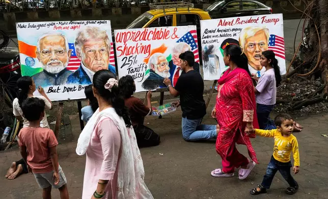 People walk by as students of Gurukul school of Art complete artwork of U.S. President Donald Trump and Prime Minister of India Narendra Modi, in Mumbai, India, Friday, Aug. 1, 2025. (AP Photo/Rajanish Kakade)
