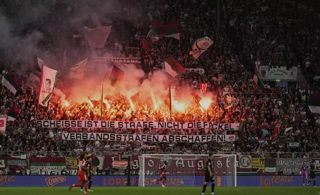 Augsburg fans celebrate with flares after their side's second goal during the Bundesliga soccer match between FC Augsburg and FC Bayern Munich in Augsburg, Germany, Aug. 30, 2025. (AP Photo/Matthias Schrader)