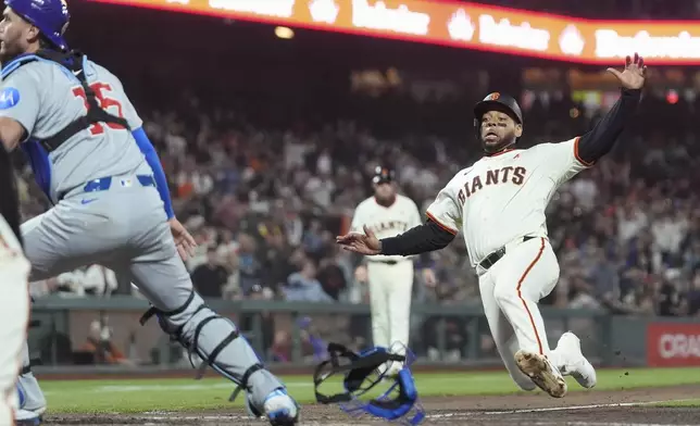 San Francisco Giants' Dominic Smith, right, slides home to score as Chicago Cubs catcher Carson Kelly, left, looks for the ball during the fifth inning of a baseball game in San Francisco, Wednesday, Aug. 27, 2025. (AP Photo/Jeff Chiu)
