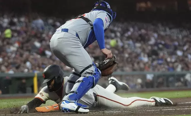 San Francisco Giants' Heliot Ramos, bottom, slides home to score under Chicago Cubs catcher Carson Kelly during the third inning of a baseball game in San Francisco, Wednesday, Aug. 27, 2025. (AP Photo/Jeff Chiu)
