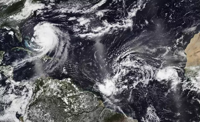In this Tuesday, Aug. 19, 2025, satellite image released by NASA, Hurricane Erin, left, continues its slow west-northwest trajectory across the Atlantic Ocean, as the National Hurricane Center is watching two more clusters of Cape Verde storms off the west coast of Africa, right, that could develop into tropical storms. (NASA Worldview, Earth Observing System Data and Information System (EOSDIS) via AP)