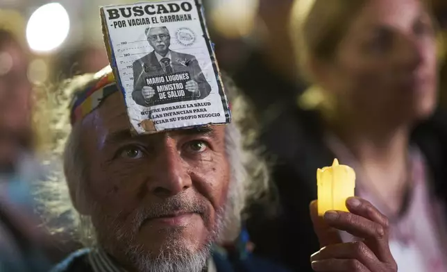 A demonstrator holds a candle while wearing a "wanted" sign of Heath Minister Mario Lugones on his forehead during a demonstration to demand better salaries and increased funding for the Garrahan pediatric public Hospital, in Buenos Aires, Argentina, Thursday, July 31, 2025. (AP Photo/Rodrigo Abd)