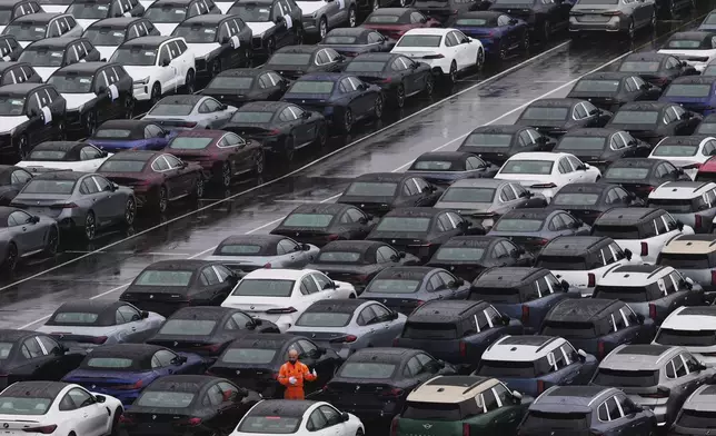 A worker checks on new cars parked in a lot at the International Car Operators terminal in the Port of Zeebrugge, Belgium, Thursday, July 31, 2025. (AP Photo/Virginia Mayo)