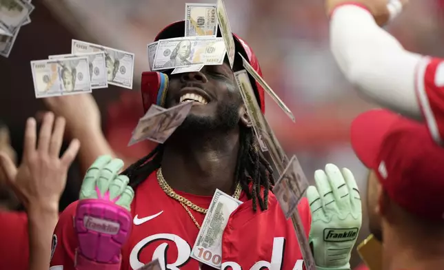 Teammates shower Cincinnati Reds' Elly De La Cruz with play money in the dugout after his two-run homer during the third inning of a baseball game against the Atlanta Braves, in Cincinnati, Thursday, July 31, 2025. (AP Photo/Carolyn Kaster)