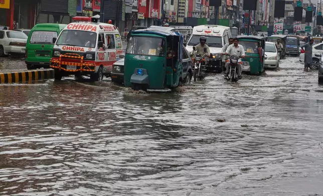 Vehicles and motorcyclists drive through a flooded road after heavy rainfall in Peshawar, Pakistan, Monday, Aug. 18, 2025. (AP Photo/Muhammad Sajjad)