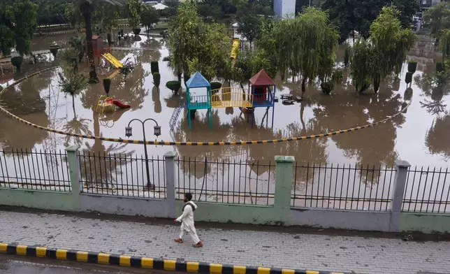 A man walks past a flooded park after heavy rainfall in Peshawar, Pakistan, Monday, Aug. 18, 2025. (AP Photo/Muhammad Sajjad)
