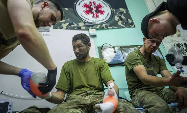 Ukrainian medics of Da Vinci Wolves Battalion treat their injured comrades at a stabilisation point on Pokrovsk direction, Ukraine, Sunday, Aug. 10, 2025. (AP Photo/Evgeniy Maloletka)