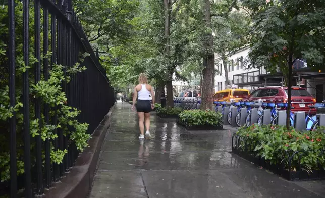 A woman walks in the rain next to Gramercy Park, Thursday, July 31, 2025, in New York. (AP Photo/Pamela Hassell)