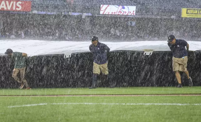 The Grounds crew roll out the tarp during a rain delay in the fifth inning of a baseball game between the New York Yankees and the Tampa Bay Rays, Thursday, July 31, 2025, in New York. (AP Photo/Heather Khalifa)