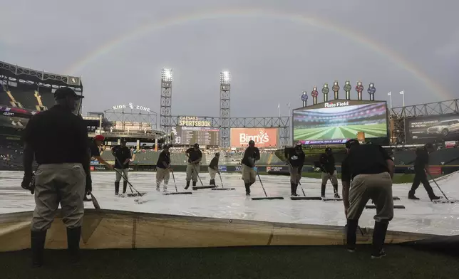 A rainbow is seen as grounds crew members clear water off a tarp prior to a baseball game between the Chicago White Sox and the Detroit Tigers, Tuesday, Aug. 12, 2025 in Chicago. (AP Photo/Talia Sprague)